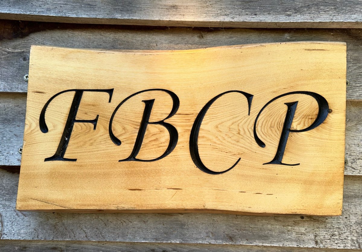 Hand-carved wooden sign reading FBCP outside the Fen Bridge clinic near Royston